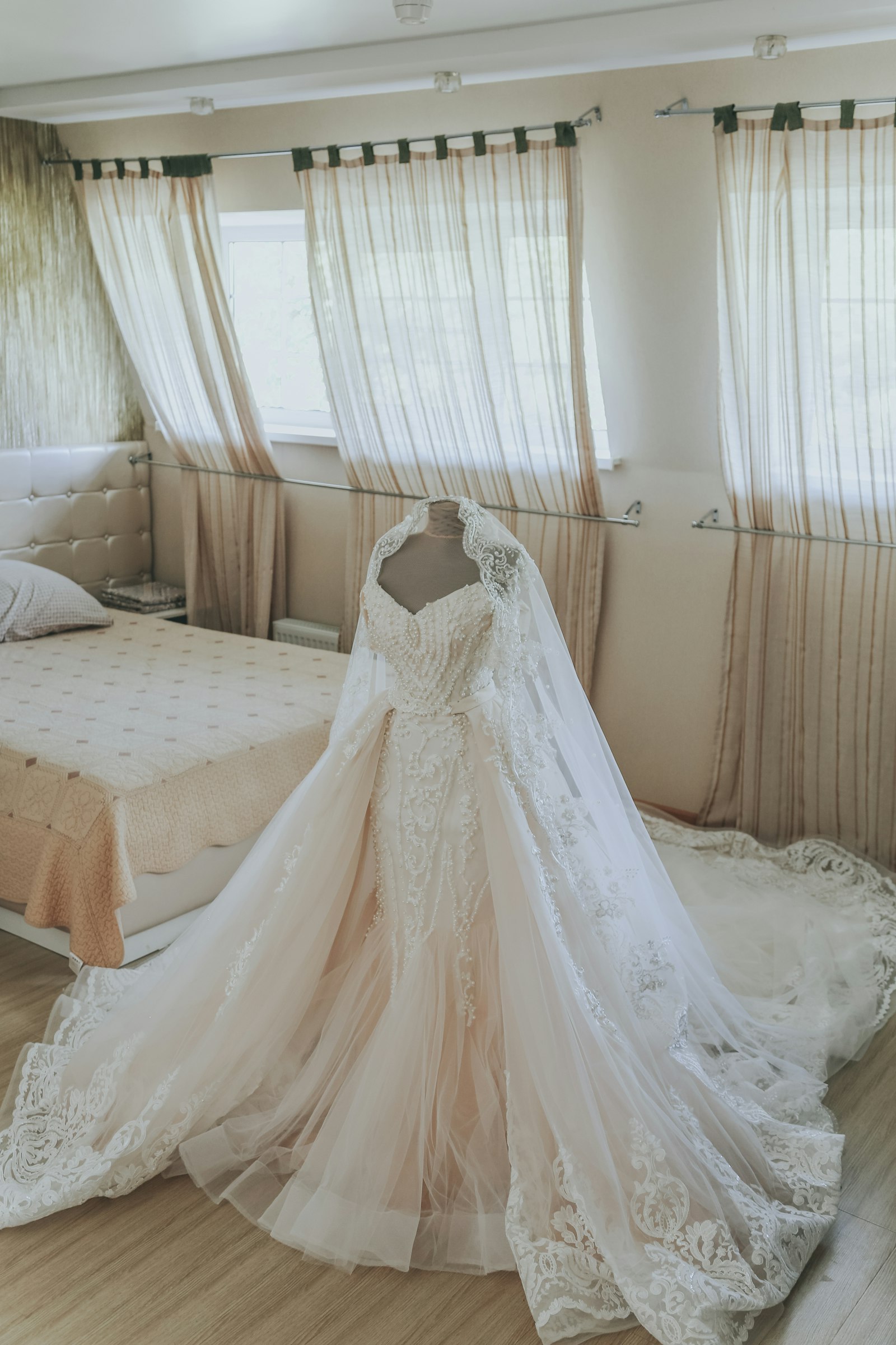 A wedding dress and veil hanging in morning light